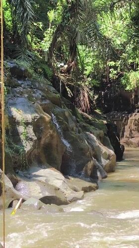 Turbulent river flows through Indonesian gorge amid tropical scenery