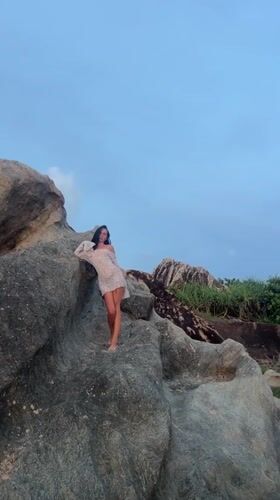 Woman poses on coastal rocks in Wellabada, Sri Lanka