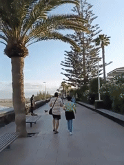 Evening stroll captured along Spanish coastal promenade with street vendors