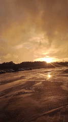 Post-rain rainbow and golden light over wet Belarusian parking lot