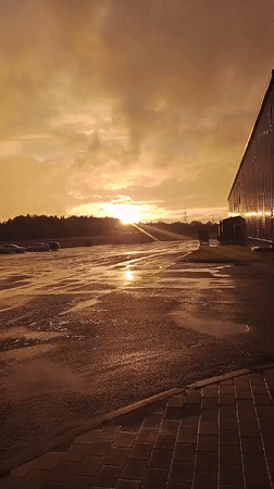 Post-rain rainbow and golden light over wet Belarusian parking lot