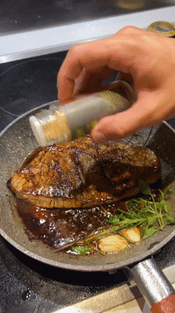 Steak seasoning in progress on a Milan stovetop