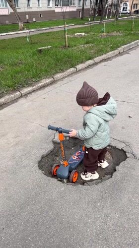 Toddler rides scooter through Klin streets during family outing