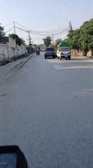 Motorcycle with large tarp covering travels through Peshawar streets