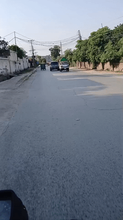Motorcycle with large tarp covering travels through Peshawar streets
