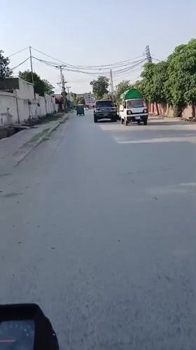 Motorcycle with large tarp covering travels through Peshawar streets