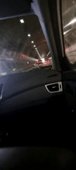 Car drives through lit tunnel with traffic ahead