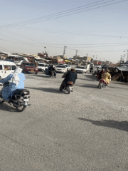 Rush hour traffic flows through dusty Quetta intersection