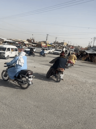 Rush hour traffic flows through dusty Quetta intersection