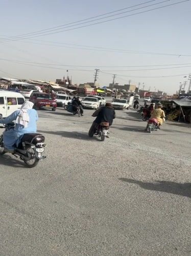 Rush hour traffic flows through dusty Quetta intersection