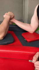 Men compete in arm-wrestling match at gym facility