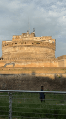 Man walks past Castel Sant'Angelo on overcast Rome afternoon