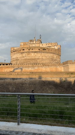 Man walks past Castel Sant'Angelo on overcast Rome afternoon