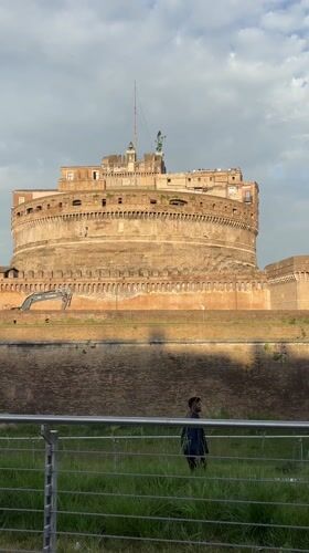 Man walks past Castel Sant'Angelo on overcast Rome afternoon
