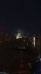 White fireworks light up night sky over residential area