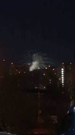 White fireworks light up night sky over residential area
