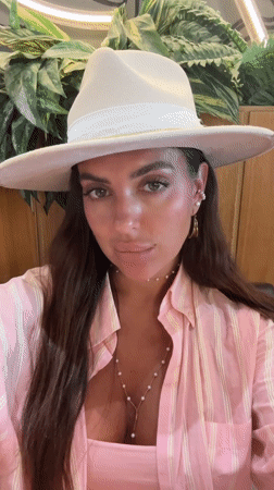 Woman takes selfies in fedora and stripes in Dubai