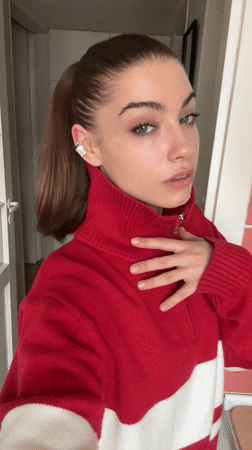 Woman adjusts sweater zipper indoors in Moscow