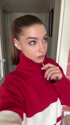 Woman adjusts sweater zipper indoors in Moscow