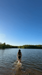 Woman enjoys afternoon swim at forest lake in Chernushka