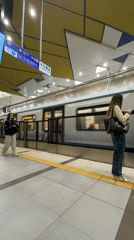 Two women wait on Sofia subway platform, one checking phone