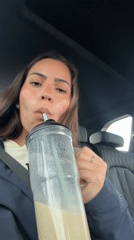 Woman drinks from tumbler while in car in Ixtapaluca