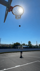 Man plays basketball on sunny morning in Vysoky, Russia
