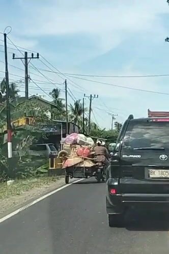Cargo motorcycle and SUV share a rural Indonesian road