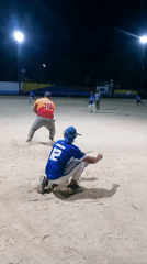 Nighttime baseball game played on sand field under lights