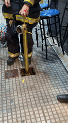 Firefighters operate equipment on Buenos Aires street at night