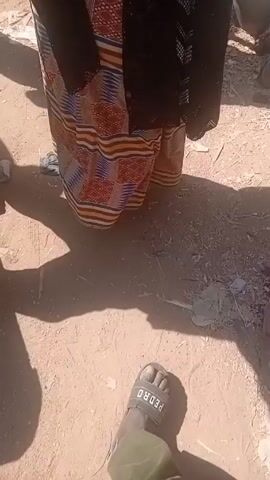 The video captures a bustling market scene. Various individuals can be seen engaging in the activity of buying and selling grains, legumes, and other goods.  Containers and bags of these products are prominent. People in colorful traditional attire navigate the crowded space.