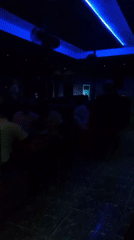 Evening social gathering at bar with colorful lighting, pool