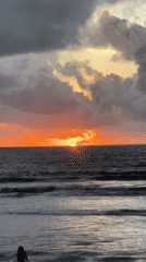 Tourists enjoy dramatic sunset at Kuta Beach Indonesia