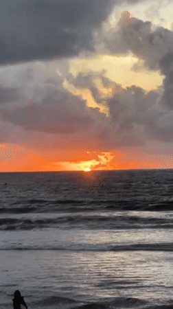 Tourists enjoy dramatic sunset at Kuta Beach Indonesia