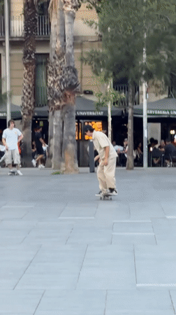 Skateboarders perform tricks in Barcelona plaza during evening session