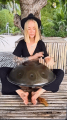 Street musician performs handpan drum outdoors in natural setting