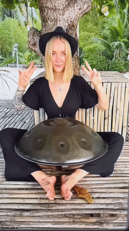 Street musician performs handpan drum outdoors in natural setting