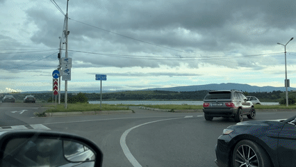 Afternoon traffic flows along lakeside road near Tbilisi mountains