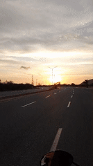 Motorcycle rider captures sunset journey on empty road