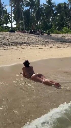 Woman relaxes in shallow beach water, early morning Philippines
