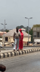 Two pedestrians walk along striped curb in Lokoja, Nigeria