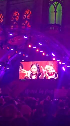 Crowd gathers at illuminated Canadian Parliament Buildings with stage setup