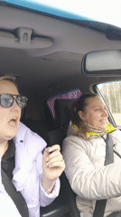 Two women sing along to music while driving in Chaikovsky