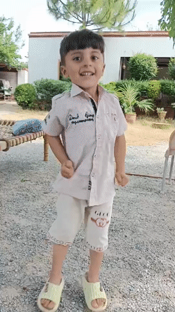 Child plays in yard with chickens in Pakistan