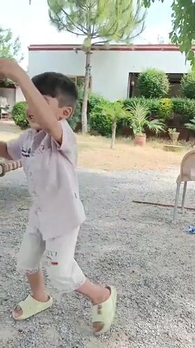 Child plays in yard with chickens in Pakistan