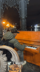 Orange piano played outdoors by Yekaterinburg waterfront at night