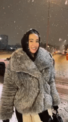 Woman in winter coat stands outside during Moscow snowfall