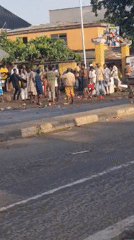 Group gathers on Lagos sidewalk with red objects scattered