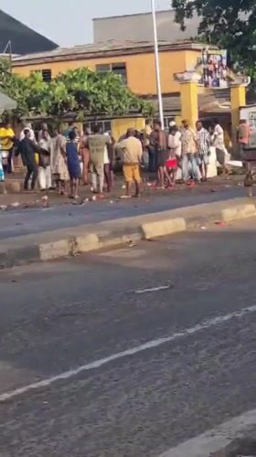Group gathers on Lagos sidewalk with red objects scattered