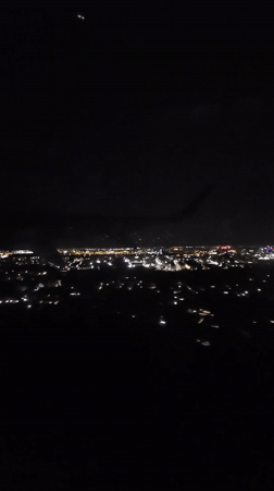 Passenger films nighttime aerial view of illuminated Bucharest from airplane